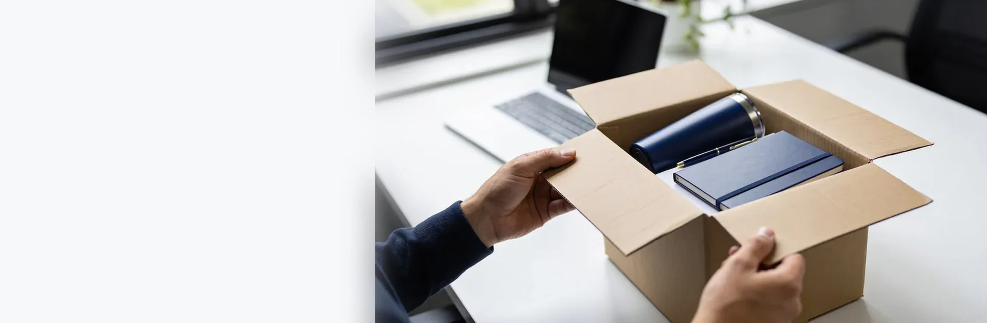 Manos abriendo una caja de envío con un termo azul y libretas dentro